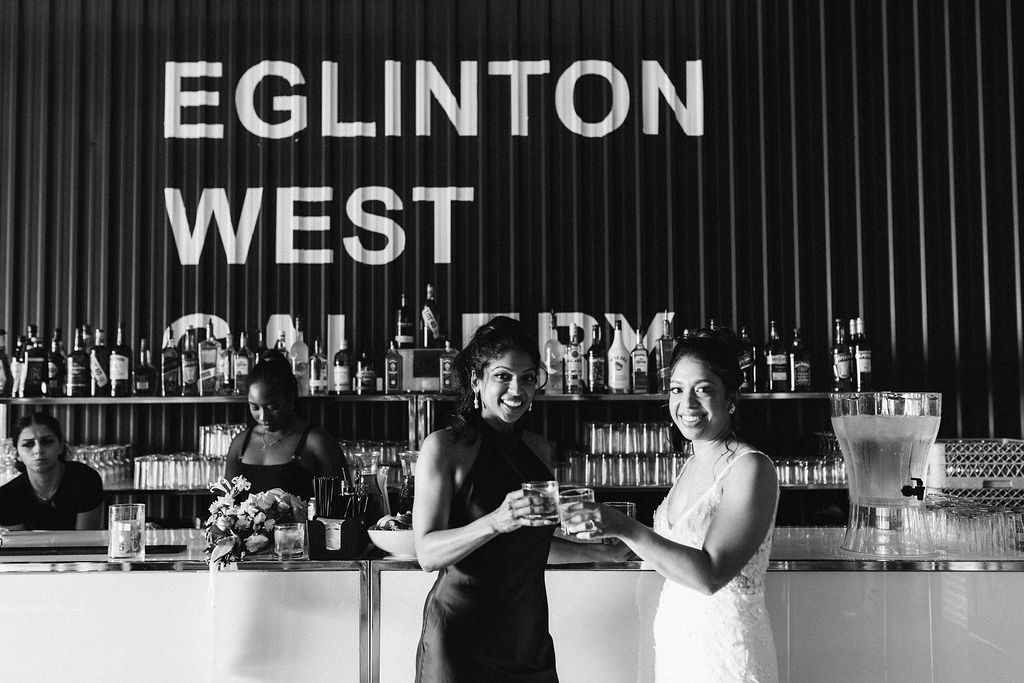 Bride and bridesmaid sharing a cheers at the Eglinton West Gallery bar