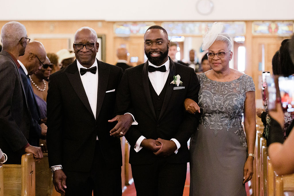 Groom walks down the aisle with father and mother