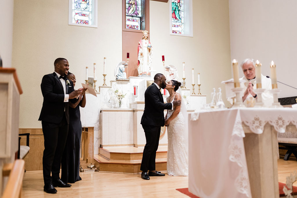 Bride and groom kissing behind altar after being married