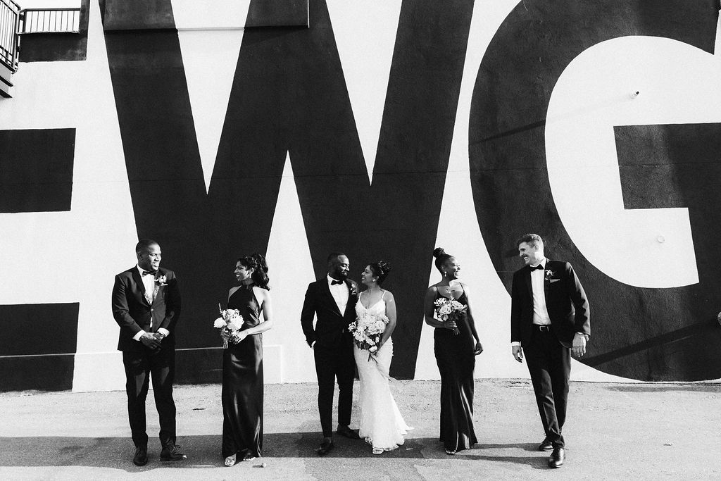 Wedding party posing with EWG graphic on the exterior wall at Eglinton West Gallery wedding